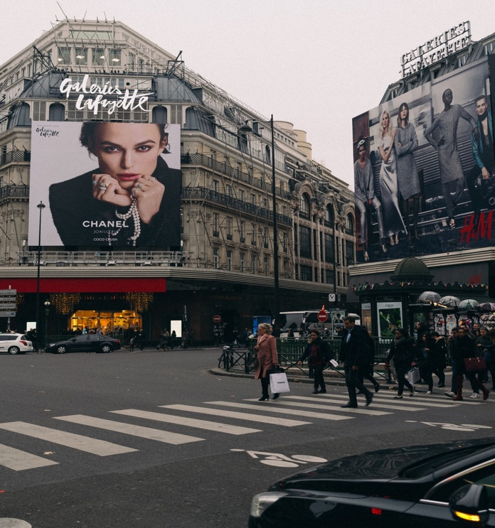 Pedestrians Crossing the Road Across a Building Featuring a Chanel Billboard